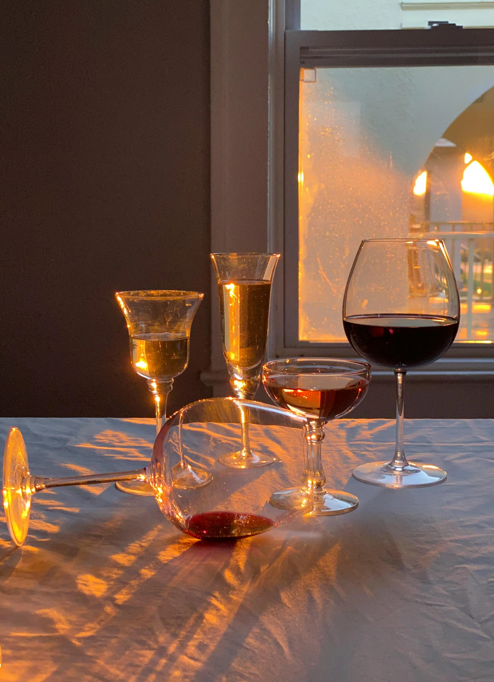 a couple of wine glasses sitting on top of a table, in the evening