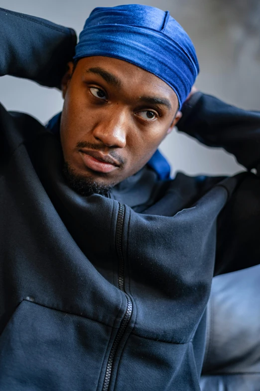 a man in a blue turban sitting on a couch, inspired by Paul Georges, trending on pexels, wearing a black hoodie, mkbhd, bo burnham, non binary model