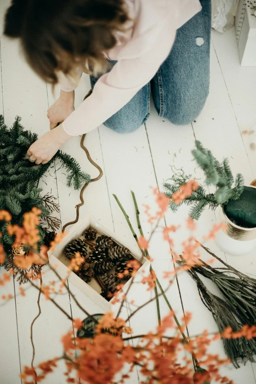 a woman sitting on the floor making a wreath, winter vibes, winding branches, professionally made, dwell