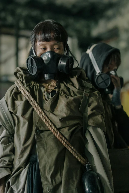 a group of people standing next to each other wearing gas masks, an album cover, by Sun Kehong, trending on pexels, military vest, [ theatrical ], scene from live action movie, woman in a dark factory