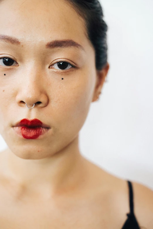 a close up of a woman with a red lipstick, an album cover, inspired by Xie Huan, trending on pexels, hyperrealism, septum piercing, human staring blankly ahead, body modification, ethnicity : japanese