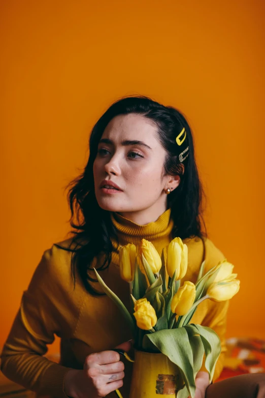 a woman holding a bouquet of yellow tulips, an album cover, by Winona Nelson, trending on pexels, maisie williams, thoughtful pose, orange hue, icon