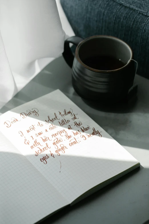 a note sitting on top of a table next to a cup of coffee, detailled light, soft window light, dark ink