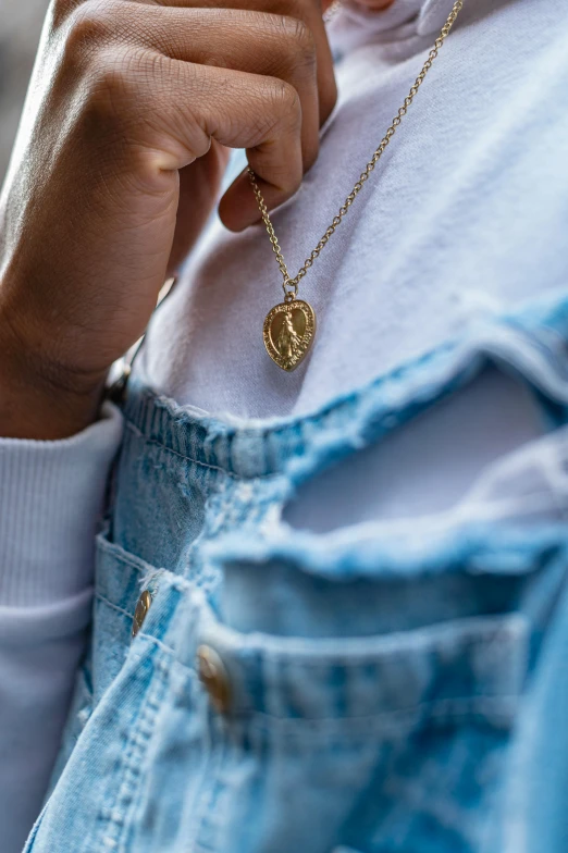 a close up of a person wearing a necklace, jeans and t shirt, gold leaf, zoomed out, wearing double denim