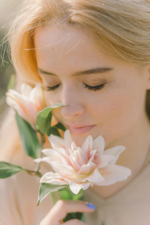 a woman holding a flower in front of her face, trending on unsplash, romanticism, close up of a blonde woman, natural soft pale skin, peach, eyes closed