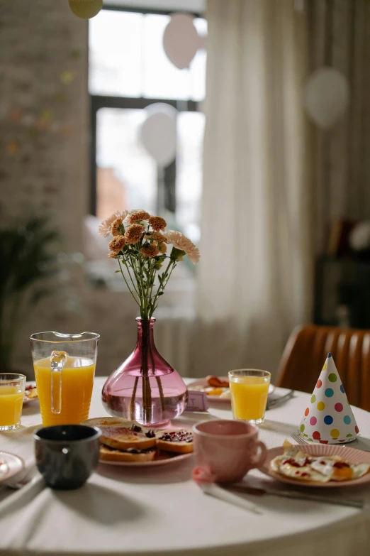 a table topped with plates of food and glasses of orange juice, pexels contest winner, hyperrealism, happy birthday, bouquet, pink, natural light in room