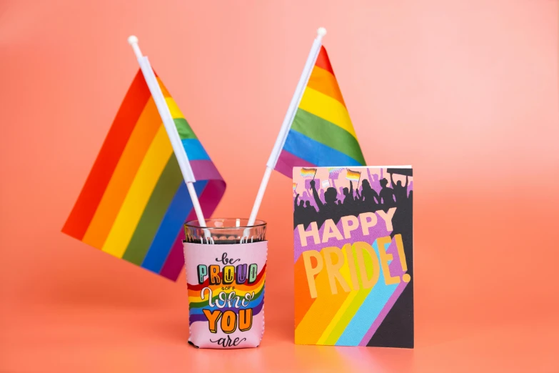 a cup of coffee next to a rainbow flag, by Julia Pishtar, pop art, on a candle holder, cheering, with a straw, product display photograph