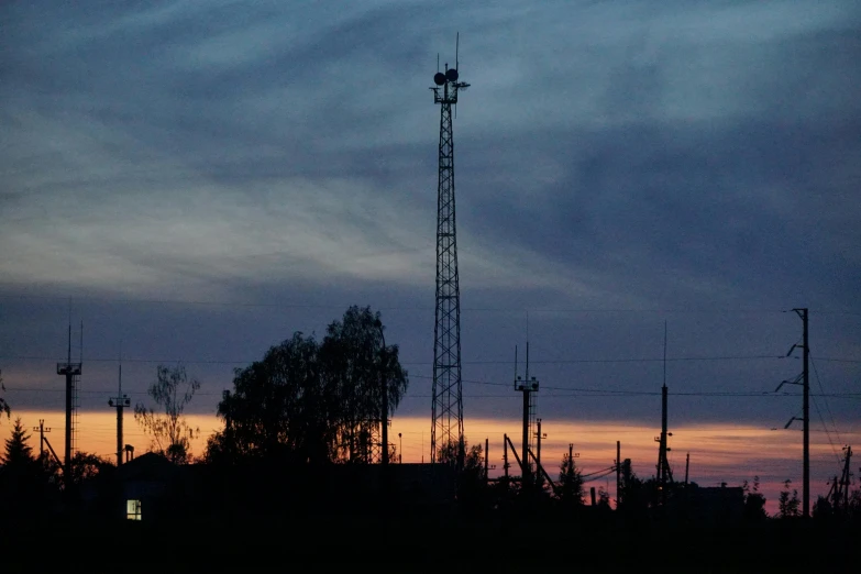 a tall tower sitting in the middle of a field, in the evening, transmitters on roof, silhouetted, busy night