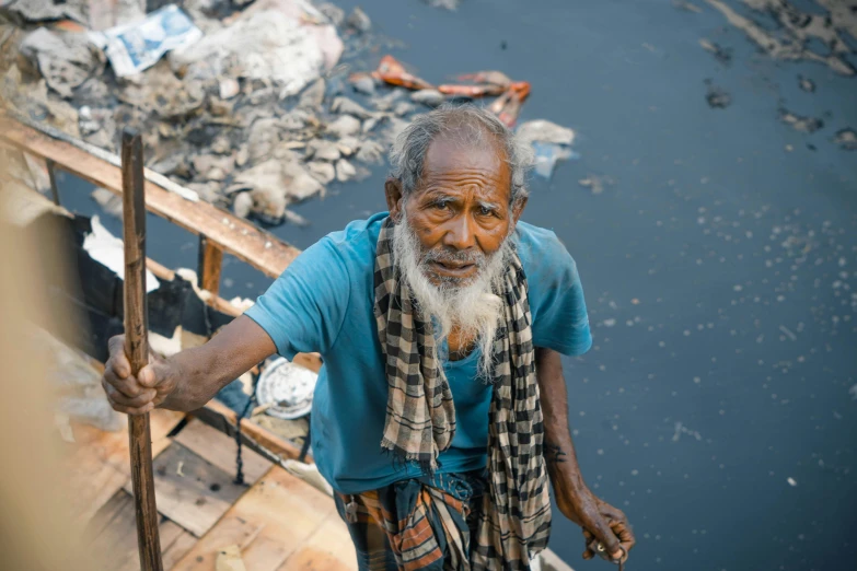 a man standing next to a body of water, a portrait, by Scott M. Fischer, pexels contest winner, hurufiyya, old dhaka, cleaned up, brown, archimedes