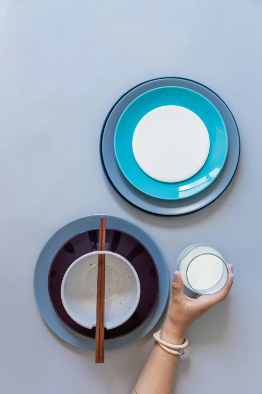 a person holding a glass of milk next to a plate with chopsticks, inspired by Constantin Hansen, minimalism, mauve and cinnabar and cyan, 4l, award winning modern design, porcelain