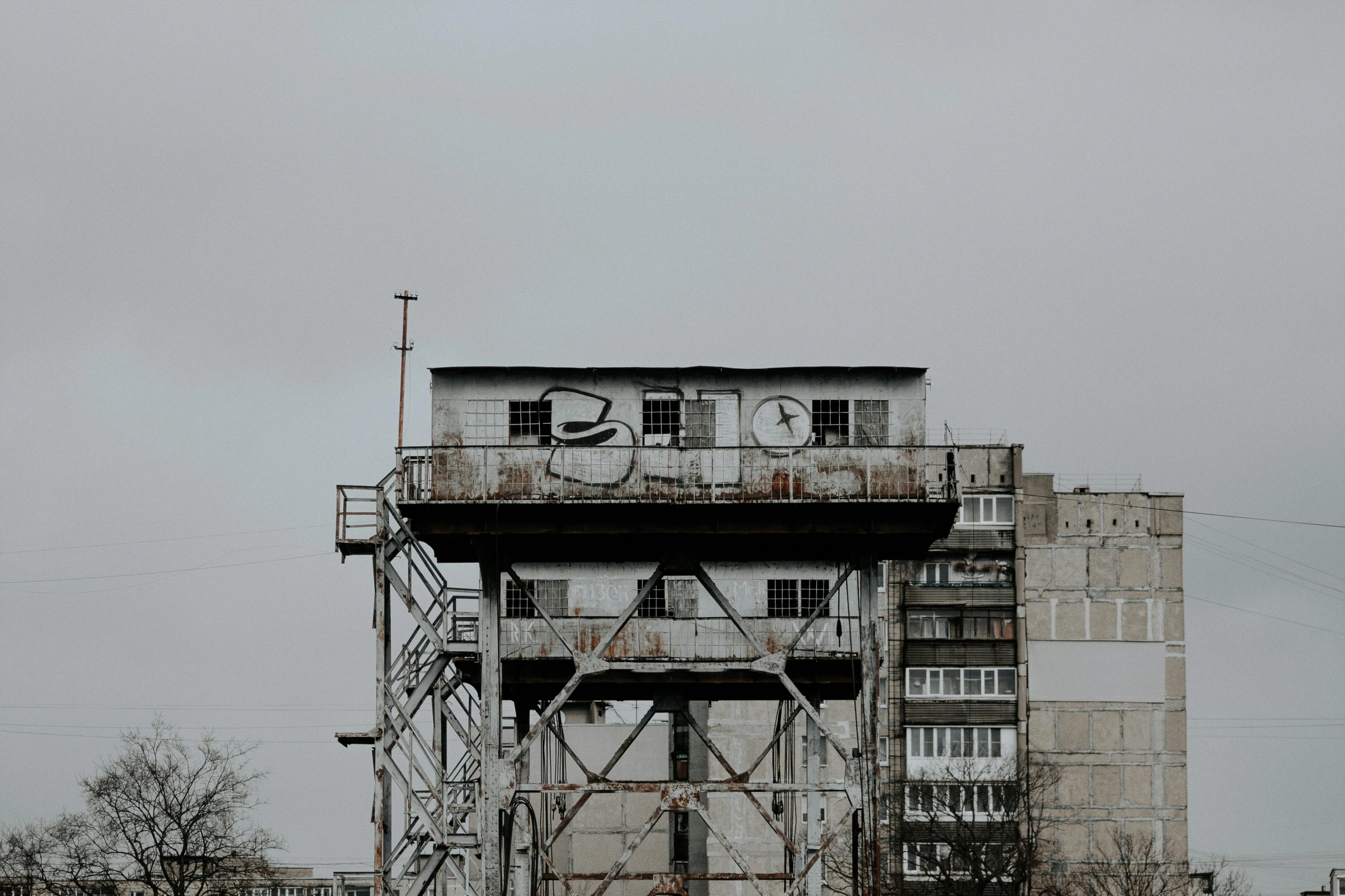 a tall building with a clock on top of it, inspired by Elsa Bleda, pexels contest winner, brutalism, old lumber mill remains, grey sky, soviet suburbs, ((rust))