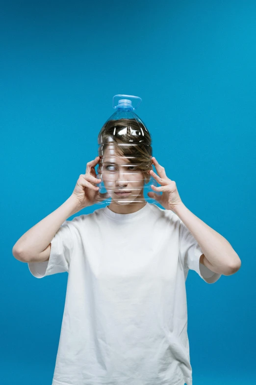 a boy holding a water bottle over his head, an album cover, by Adam Marczyński, pexels contest winner, surrealism, transparent face, fashion of the future, hair looks like a helmet, neatly coming out of her head