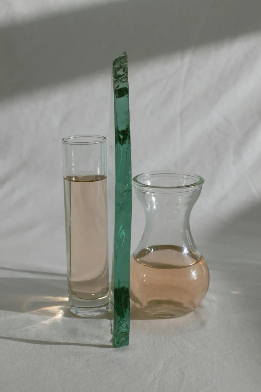 a green toothbrush sitting next to a glass of water, an album cover, inspired by Raoul De Keyser, transparent glass vase, light pink tonalities, two organic looking towers, taken in the late 2000s