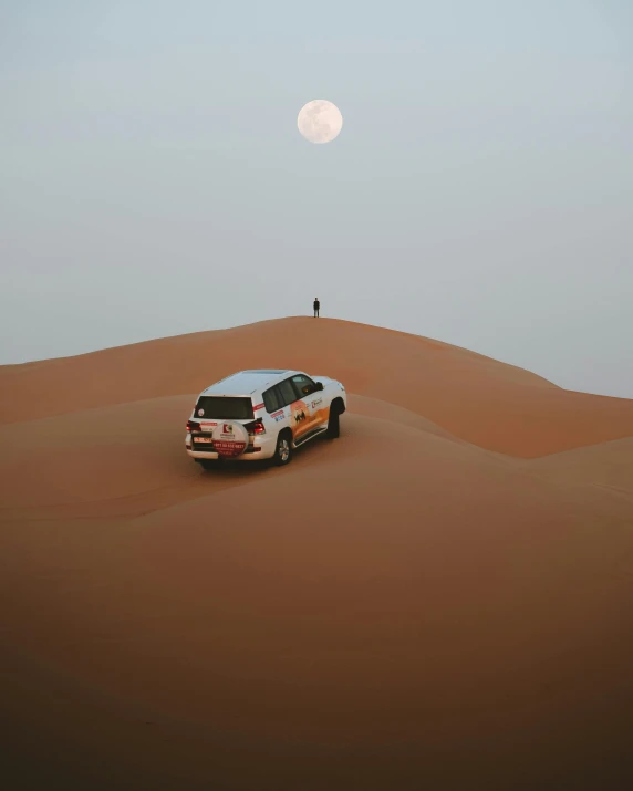 a car in the desert with a full moon in the background, pexels contest winner, dau-al-set, sheikh mohammed ruler of dubai, ☁🌪🌙👩🏾, sports photo, distant full body view