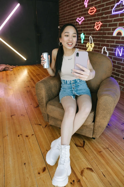 a woman sitting in a chair holding a cell phone, inspired by helen huang, instagram, round thighs, she is about 1 6 years old, holding a drink, mid air shot