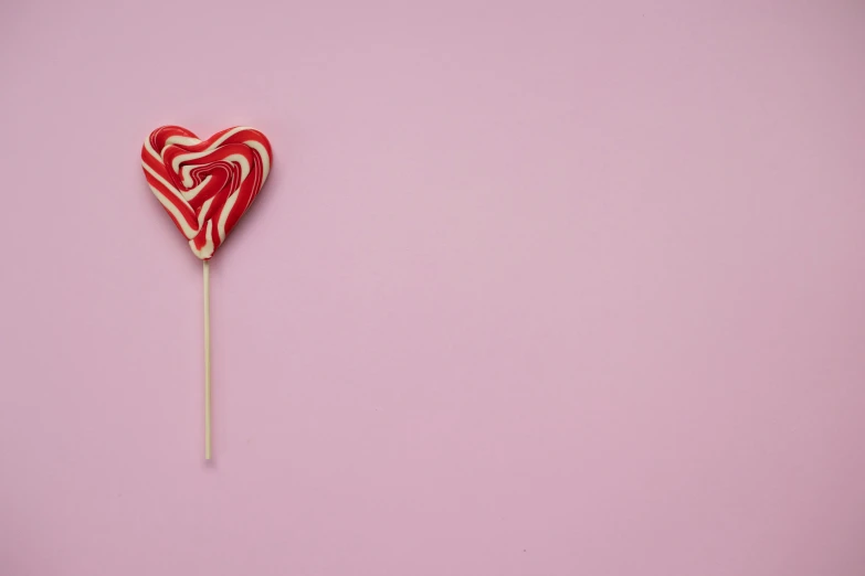 a heart shaped lollipop on a stick, by Emma Andijewska, pexels, pop art, light pink background, striped, gif, product introduction photo