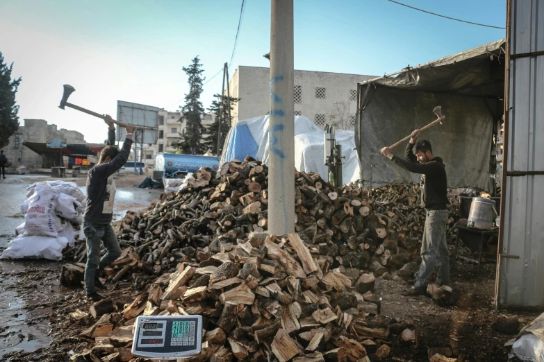 a couple of men standing next to a pile of wood, unsplash, temporary art, real life photo of a syrian man, programming, digital oth, axes