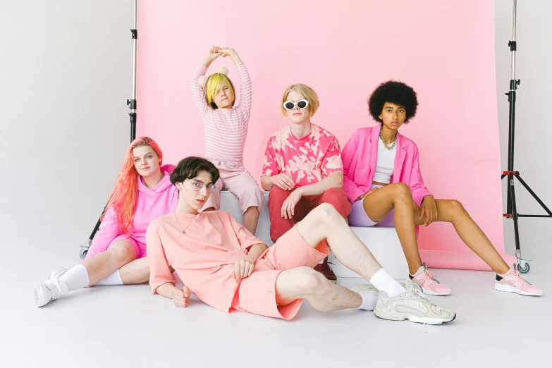 a group of people sitting in front of a pink backdrop, trending on pexels, federation clothing, pink short hair, extremely gendered, product introduction photo