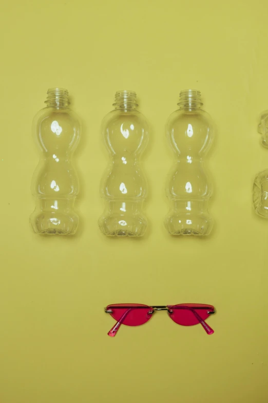 a group of plastic bottles sitting on top of a table, inspired by Jeff Koons, pexels contest winner, yellow carrera glasses, pink, symmetrical image, detail