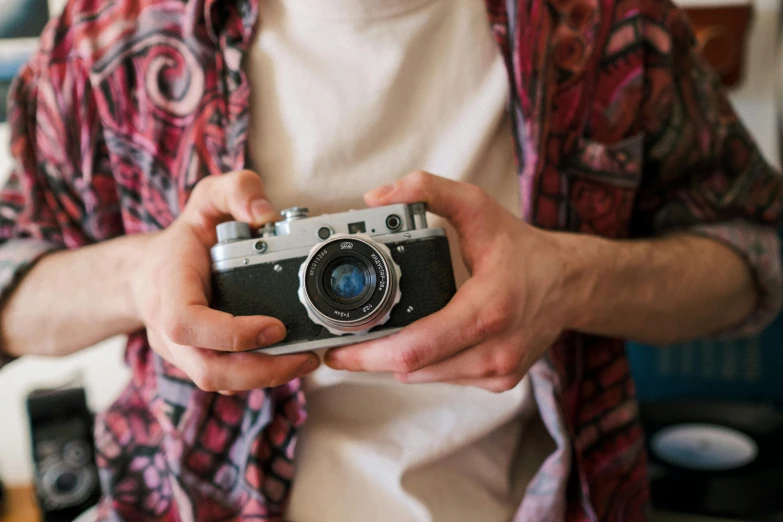a man holding a camera in his hands, a picture, by Joe Bowler, unsplash, retro colour, medium - format print, canon a1, cute photograph
