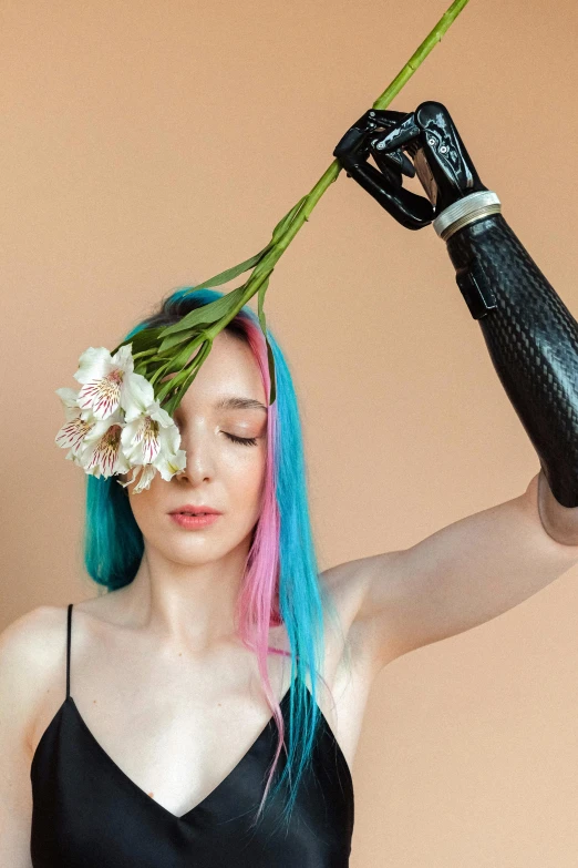 a woman holding a flower in front of her face, an album cover, inspired by Hedi Xandt, trending on pexels, aestheticism, robotic prosthetic arm, long cyan hair, crutches, looking left