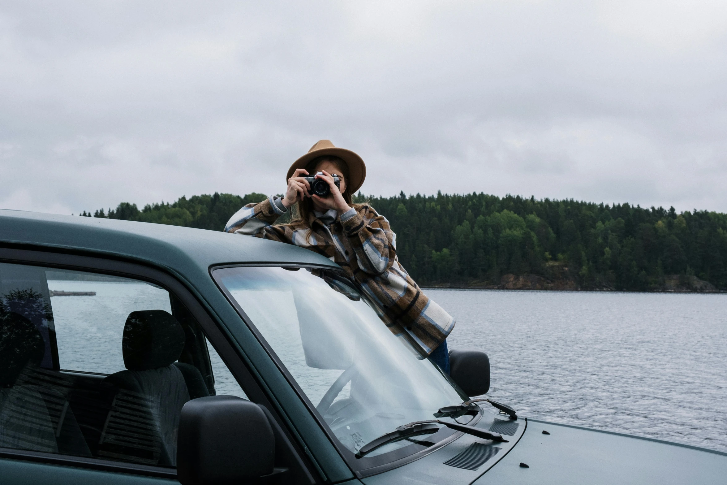 a man sitting on top of a car talking on a cell phone, by Jaakko Mattila, pexels contest winner, lake view, binoculars, sitting in her car, female looking