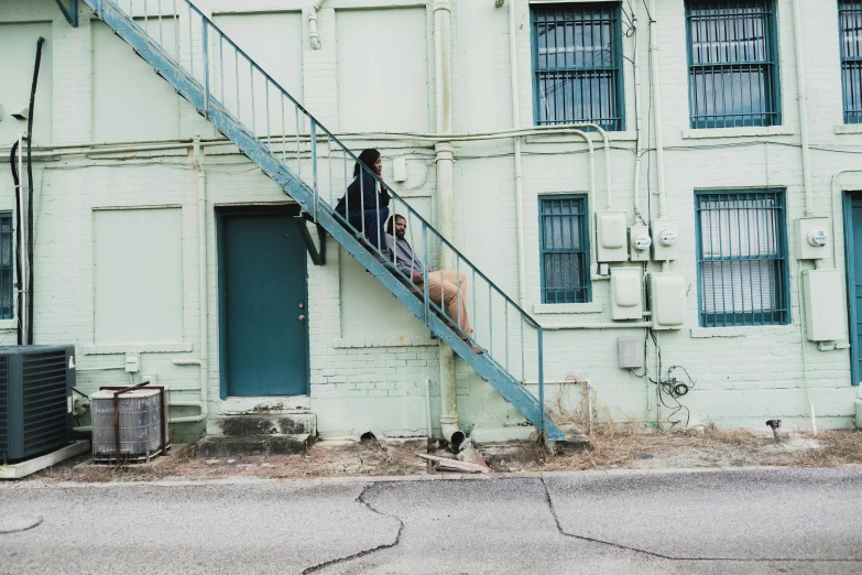 a man walking up a set of stairs in front of a building, by Andrew Stevovich, pexels contest winner, realism, two dogs, stephen shore & john j. park, green alleys, trying to escape