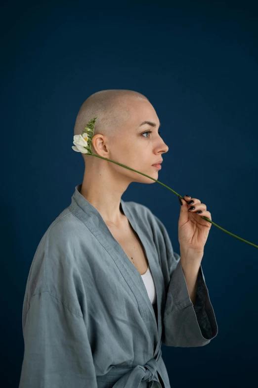 a woman with a flower in her hair, an album cover, inspired by Tani Bunchō, antipodeans, shaved bald head, wearing robe, shot with sony alpha, promotional image
