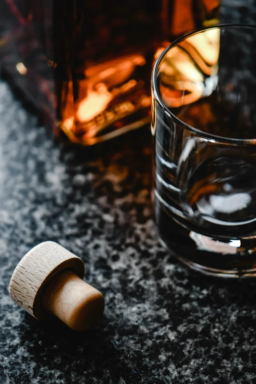 a glass of whiskey next to a bottle, unsplash, thumbnail, detail shot, brown, neck up