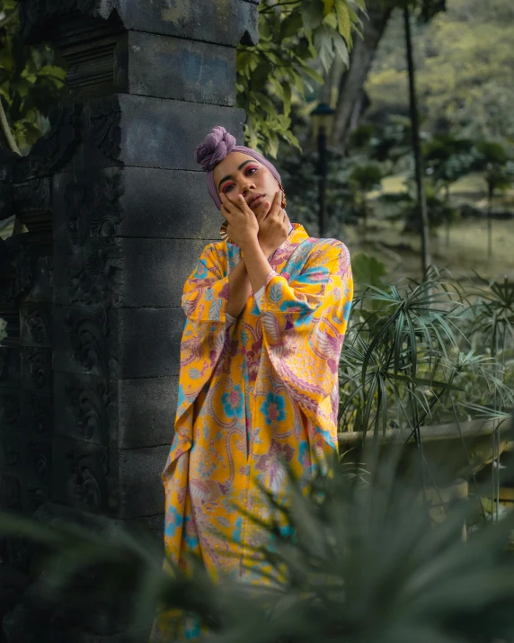 a woman standing in a garden talking on a cell phone, an album cover, inspired by I Ketut Soki, pexels contest winner, sumatraism, bathrobe, non binary model, tie-dye, doing a majestic pose