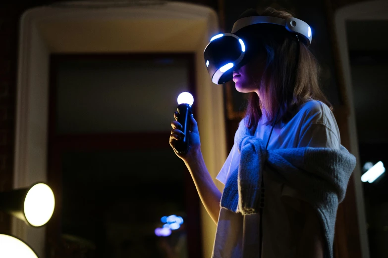 a woman using a virtual reality device in a dark room, by Julia Pishtar, unsplash, dramatic white and blue lighting, playstation, brown, wearing a gaming headset