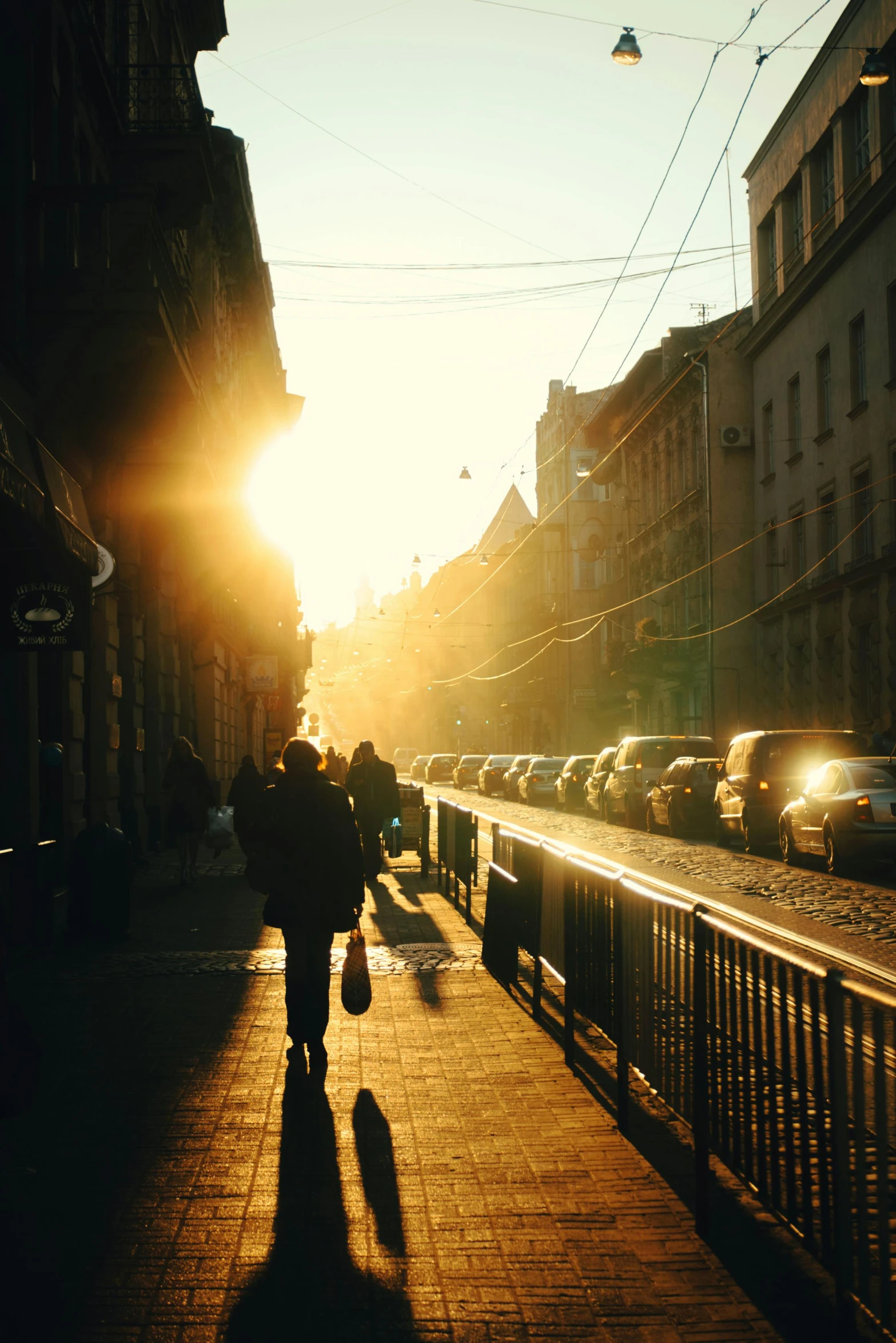 a person walking down a street at sunset, saint petersburg, full morning sun, instagram post, lviv