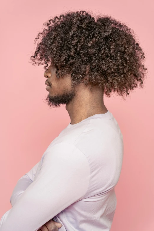 a man with curly hair standing with his arms crossed, by Cosmo Alexander, trending on pexels, pastel pink skin tone, hair : long brown, profile shot, coloured