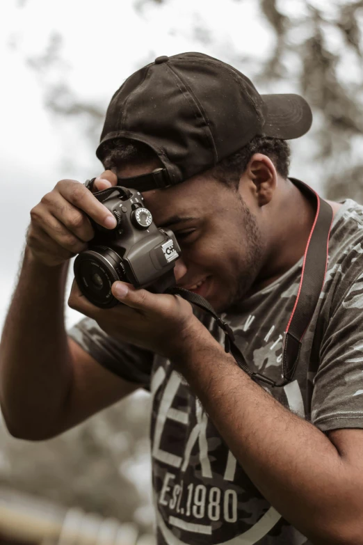 a man taking a picture with a camera, looking down on the camera, posing for the camera