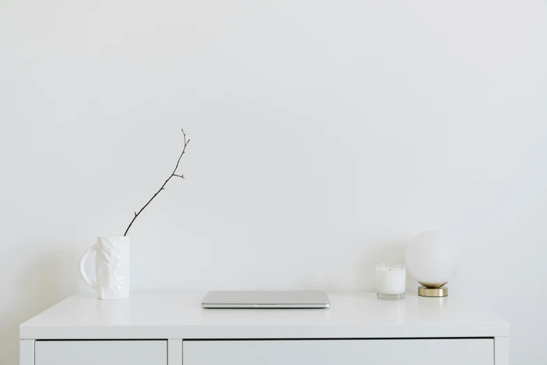 a laptop computer sitting on top of a white dresser, inspired by Eero Snellman, unsplash contest winner, minimalism, soft zen minimalist, background image, white porcelain skin, minimalist lines