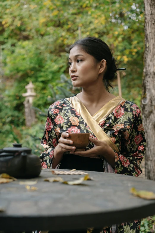 a woman in a kimono standing next to a table, inspired by Gu An, sumatraism, movie filmstill, coffee, malaysian, black