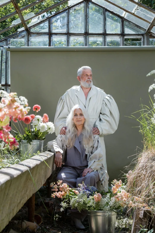 a man and a woman posing for a picture in a greenhouse, a portrait, inspired by Jean Jouvenet, unsplash, renaissance, flowy white grey hair, bathrobe, die antwoord style wear, blooming