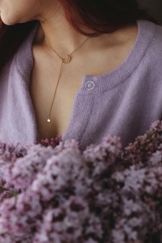 a woman holding a bouquet of purple flowers, inspired by Ruth Jên, trending on pexels, aestheticism, wearing several pendants, crescent moon, detail shot, pastel clothing