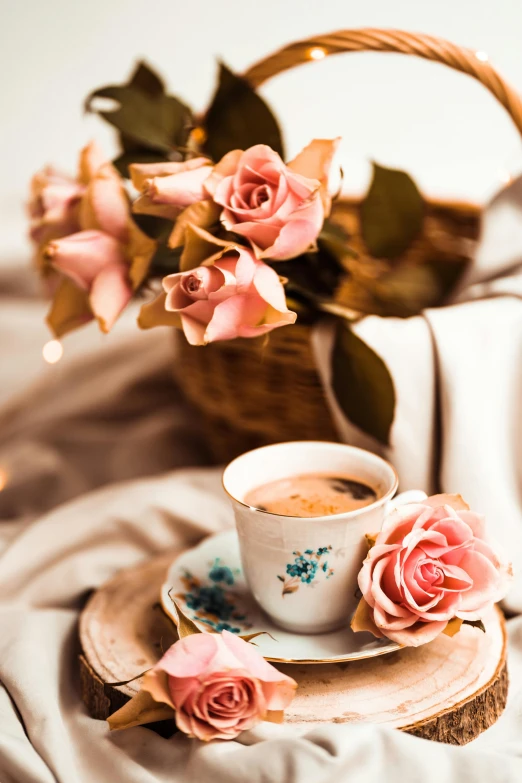 a basket filled with pink roses next to a cup of coffee, a still life, trending on pexels, romanticism, brown flowers, silky smooth, in shades of peach, table in front with a cup