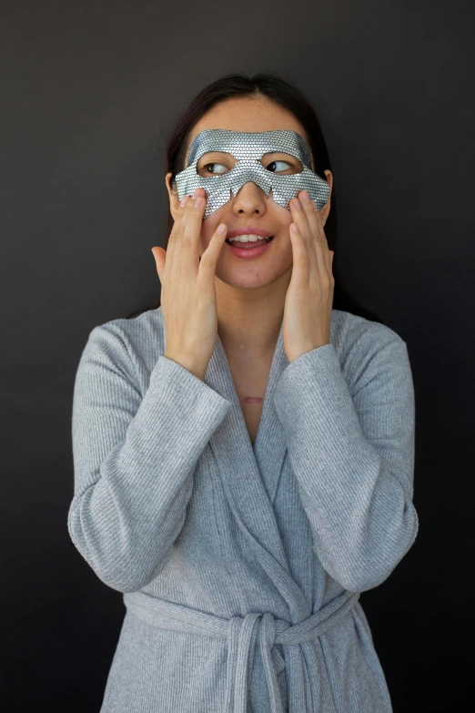a woman in a bathrobe covering her eyes, inspired by Li Di, reddit, square facial structure, grey and silver, skimask, asian woman
