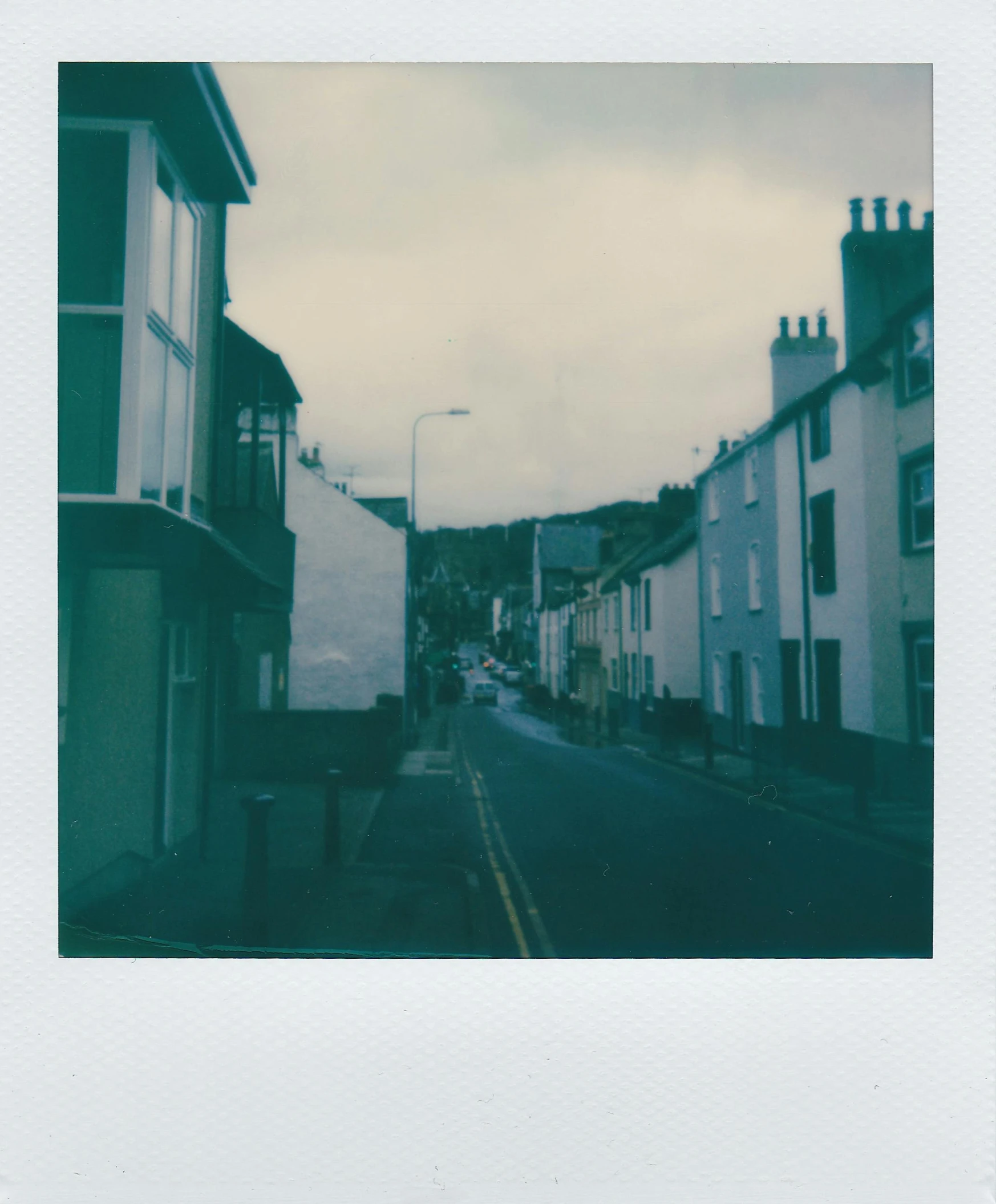 a picture of a street in a small town, a polaroid photo, by IAN SPRIGGS, unsplash, postminimalism, wales, multiple stories, medium format, slight overcast