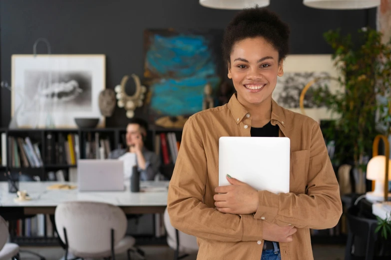 a woman standing in an office holding a laptop, pexels contest winner, academic art, black teenage girl, over his shoulder, subtle confident smile, woman holding another woman