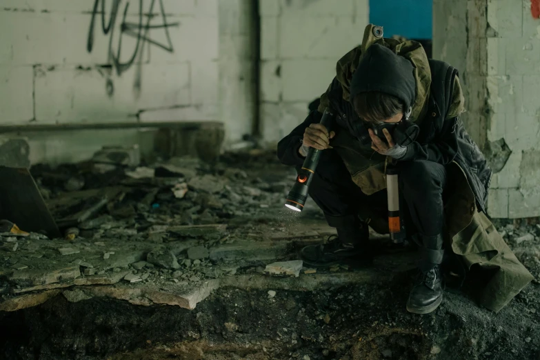 a man sitting on top of a pile of rubble, inspired by Elsa Bleda, pexels contest winner, graffiti, wearing tactical gear, in an underground laboratory, holding a small vape, instagram picture