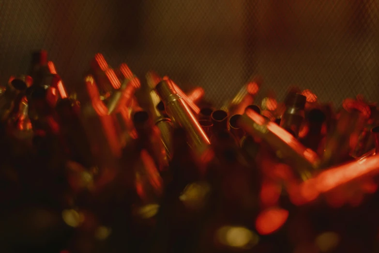 a bunch of red pens sitting on top of a table, by Attila Meszlenyi, process art, warm glow from the lights, caseless ammunition, zoomed in, made of polished broze
