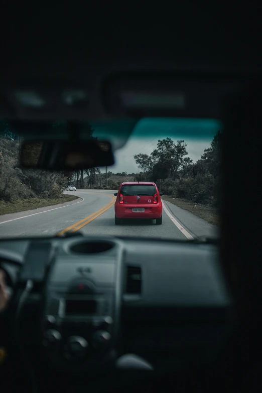 a red car driving down a road next to a forest, street view, unsplash photography, square, view from behind mirror