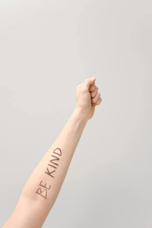 a close up of a person with a tattoo on their arm, trending on pexels, antipodeans, kindness, on a pale background, cool marketing photo, virtue