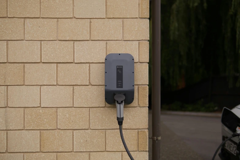 an electric charger attached to the side of a building, in gunmetal grey, bottom shot, complete scene, square