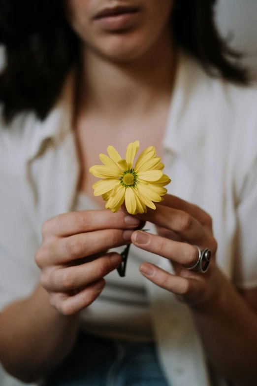 a woman holding a yellow flower in her hands, trending on unsplash, holding a holy symbol, multiple stories, fine simple delicate structure, uploaded