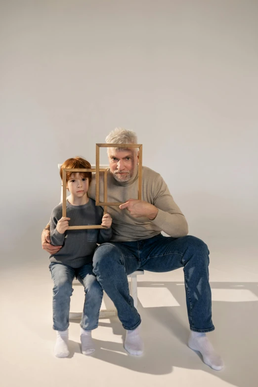 a man and a little girl sitting on a chair, a picture, pexels contest winner, conceptual art, square facial structure, picture frames, robot head and man head, blond boy