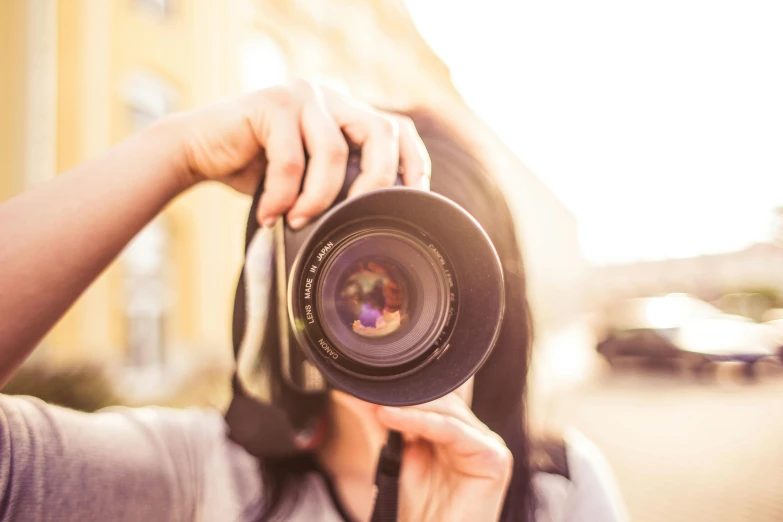 a woman taking a picture with a camera, pexels contest winner, lens zooming, lensflare, holding it out to the camera, headshot